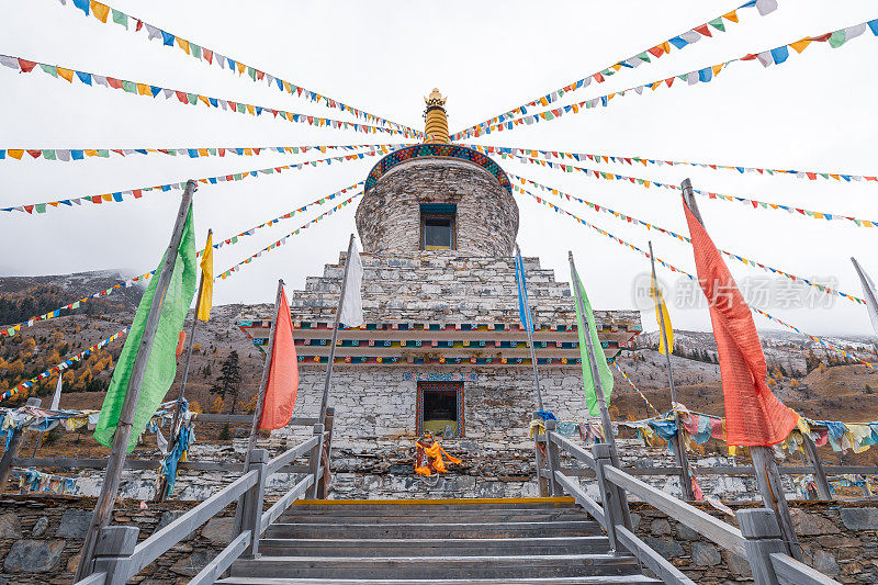 寺庙和祈祷旗亚丁/香格里拉山在秋天，中国四川，西藏在冬天多云